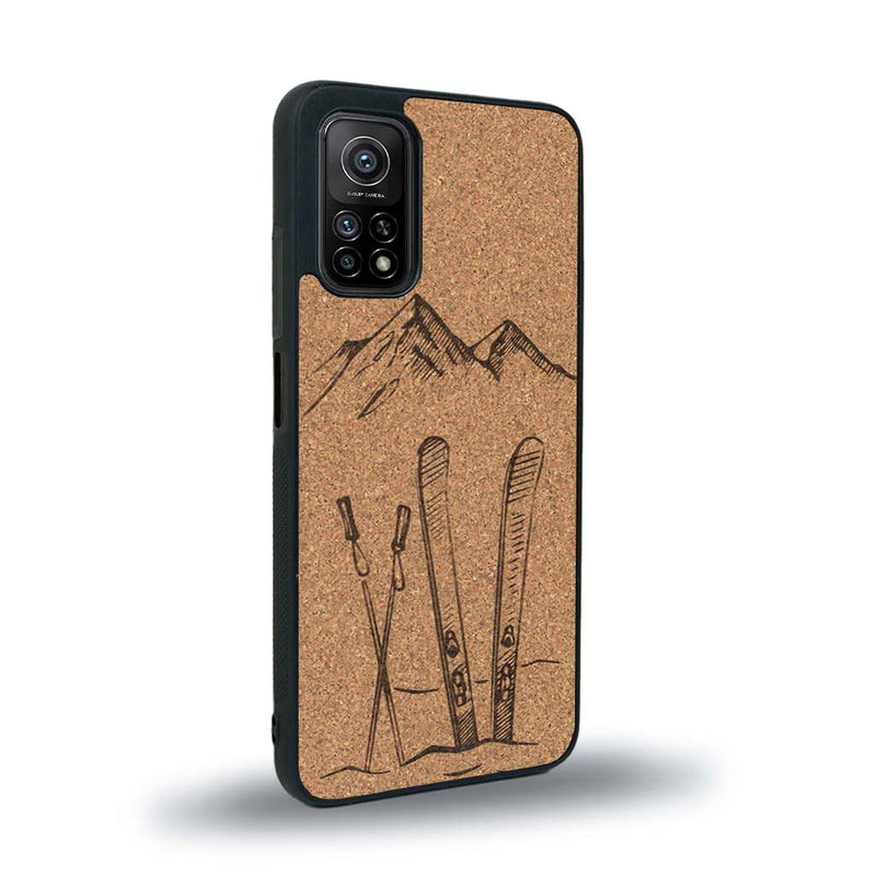 Coque de protection en bois véritable fabriquée en France pour Xiaomi Mi 10T Pro sur le thème de la montagne, du ski et de la neige avec un motif représentant une paire de ski plantée dans la neige avec en fond des montagnes enneigées