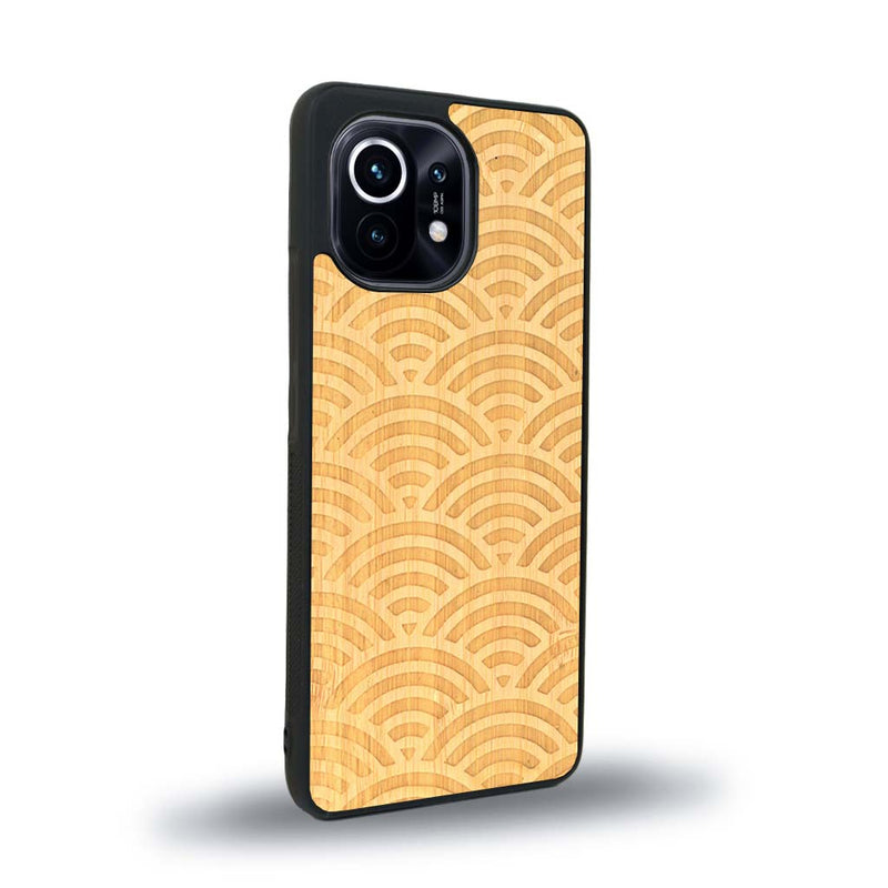 Coque de protection en bois véritable fabriquée en France pour Xiaomi Mi 11 baptisée "La Sinjak" avec un motif de gravure abstrait représentant la répétition d'un symbole wifi