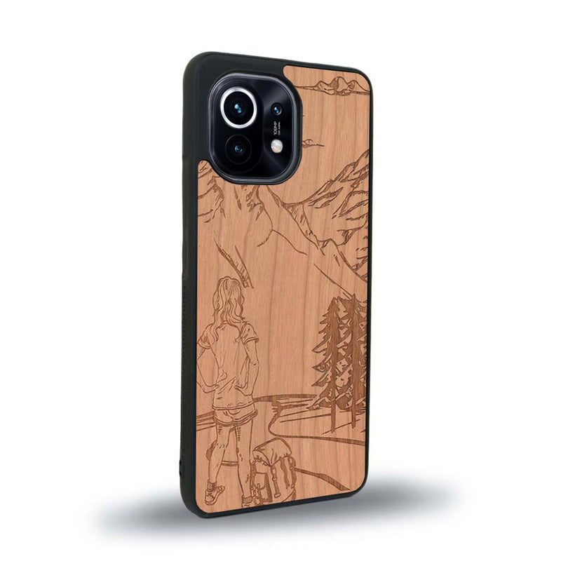 Coque de protection en bois véritable fabriquée en France pour Xiaomi Mi 11 sur le thème de la randonnée en montagne et de l'aventure avec une gravure représentant une femme de dos face à un paysage de nature