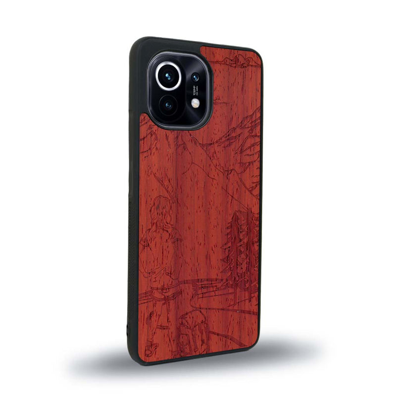 Coque de protection en bois véritable fabriquée en France pour Xiaomi Mi 11 sur le thème de la randonnée en montagne et de l'aventure avec une gravure représentant une femme de dos face à un paysage de nature