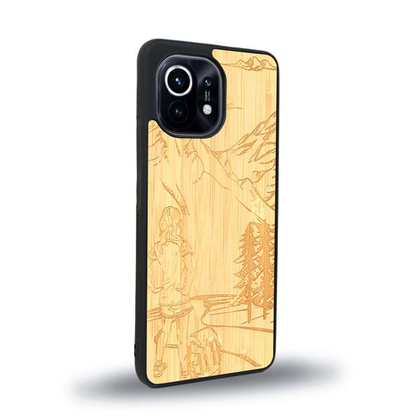 Coque de protection en bois véritable fabriquée en France pour Xiaomi Mi 11 Lite sur le thème de la randonnée en montagne et de l'aventure avec une gravure représentant une femme de dos face à un paysage de nature