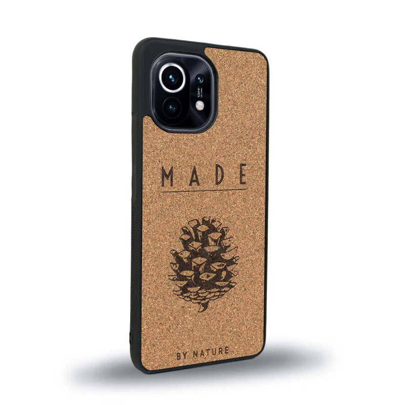 Coque de protection en bois véritable fabriquée en France pour Xiaomi Mi 11 Lite sur le thème de la nature et des arbres avec une gravure représentant une pomme de pin et la phrase "made by nature"