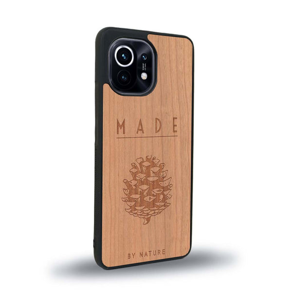 Coque de protection en bois véritable fabriquée en France pour Xiaomi Mi 11 Lite sur le thème de la nature et des arbres avec une gravure représentant une pomme de pin et la phrase "made by nature"