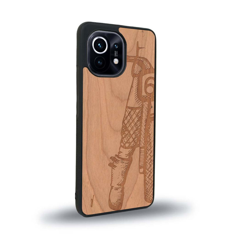 Coque de protection en bois véritable fabriquée en France pour Xiaomi Mi 11 Lite représentant une vue de face d'une femme sur une moto vintage dessinée à la main par l'artiste Maud Dabs