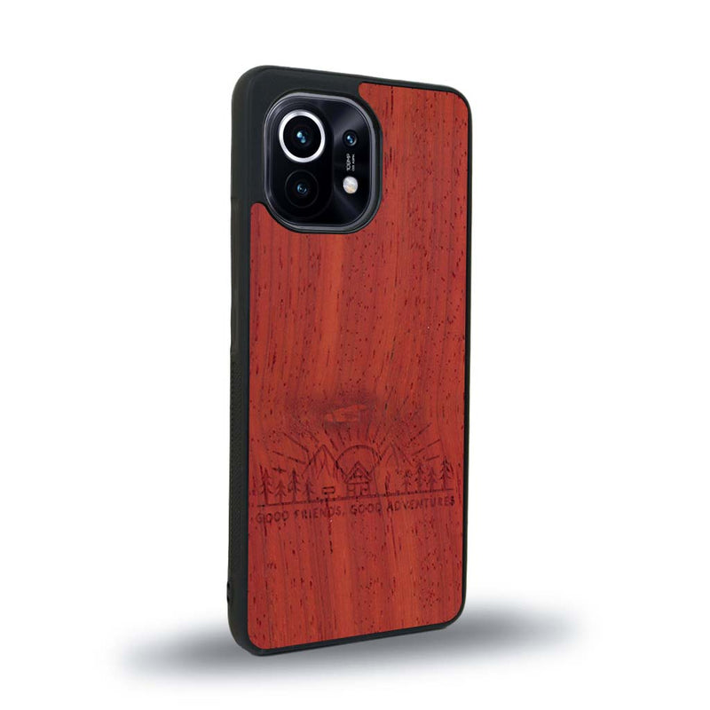 Coque de protection en bois véritable fabriquée en France pour Xiaomi Mi 11 Lite sur le thème chill et nature avec un motif représentant un levé de soleil sur un paysage de montagne avec des sapins et un chalet et la phrase "Good friends, good adventure"