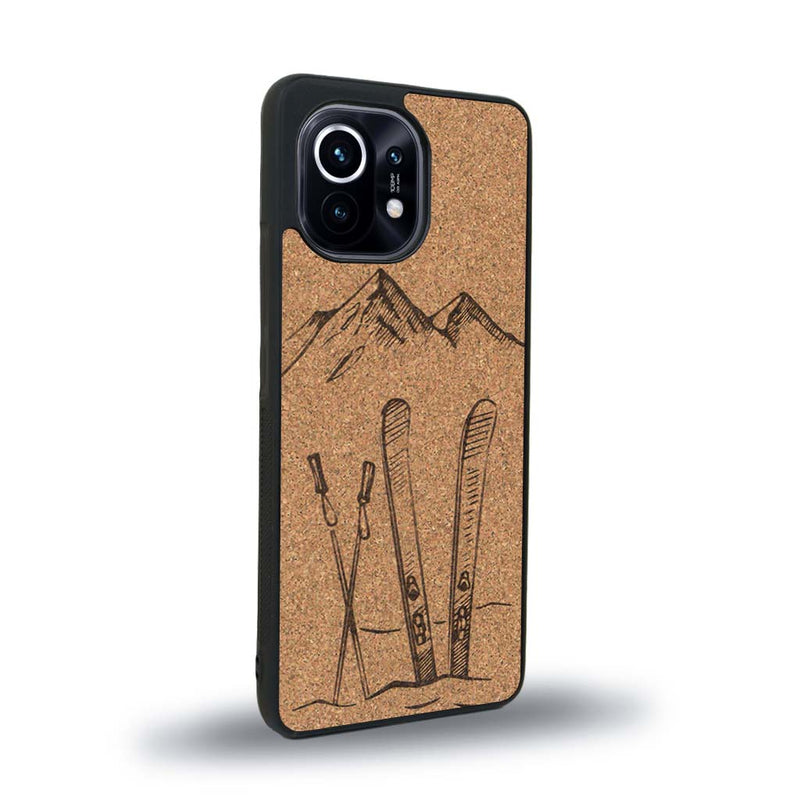 Coque de protection en bois véritable fabriquée en France pour Xiaomi Mi 11 Lite sur le thème de la montagne, du ski et de la neige avec un motif représentant une paire de ski plantée dans la neige avec en fond des montagnes enneigées