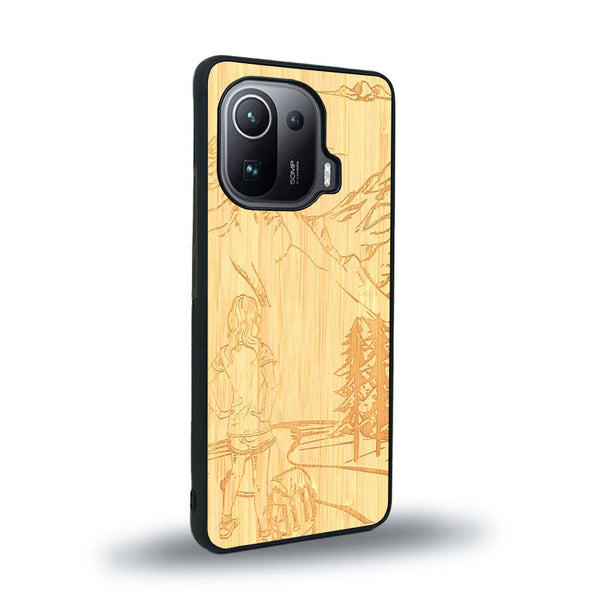 Coque de protection en bois véritable fabriquée en France pour Xiaomi Mi 11 Pro sur le thème de la randonnée en montagne et de l'aventure avec une gravure représentant une femme de dos face à un paysage de nature