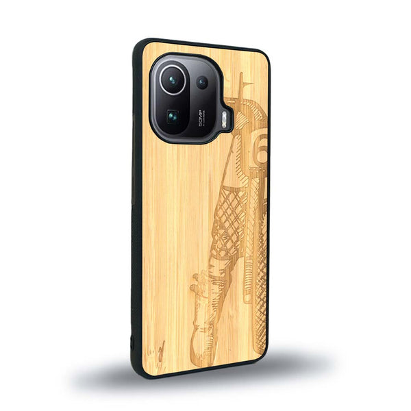 Coque de protection en bois véritable fabriquée en France pour Xiaomi Mi 11 Pro représentant une vue de face d'une femme sur une moto vintage dessinée à la main par l'artiste Maud Dabs