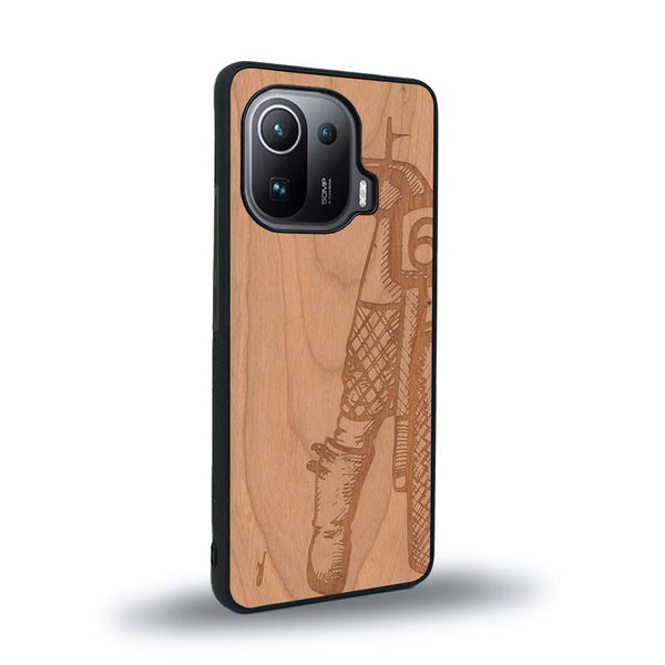 Coque de protection en bois véritable fabriquée en France pour Xiaomi Mi 11 Pro représentant une vue de face d'une femme sur une moto vintage dessinée à la main par l'artiste Maud Dabs