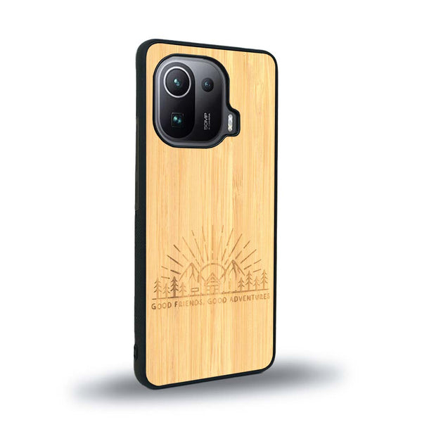 Coque de protection en bois véritable fabriquée en France pour Xiaomi Mi 11 Pro sur le thème chill et nature avec un motif représentant un levé de soleil sur un paysage de montagne avec des sapins et un chalet et la phrase "Good friends, good adventure"