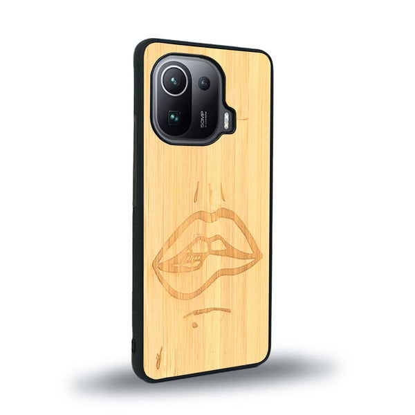 Coque de protection en bois véritable fabriquée en France pour Xiaomi Mi 11 Pro représentant de manière minimaliste une bouche de féminine se mordant le coin de la lèvre de manière sensuelle dessinée à la main par l'artiste Maud Dabs
