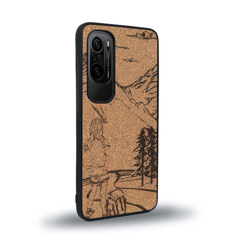 Coque de protection en bois véritable fabriquée en France pour Xiaomi Mi 11i sur le thème de la randonnée en montagne et de l'aventure avec une gravure représentant une femme de dos face à un paysage de nature