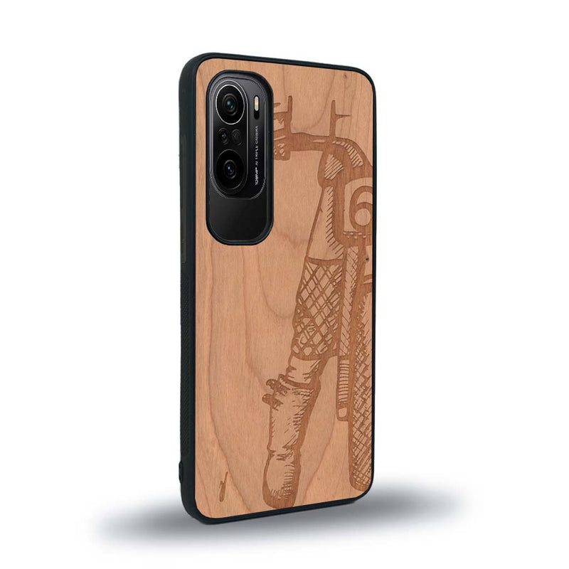 Coque de protection en bois véritable fabriquée en France pour Xiaomi Mi 11i représentant une vue de face d'une femme sur une moto vintage dessinée à la main par l'artiste Maud Dabs