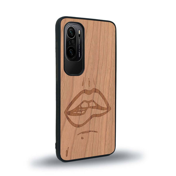 Coque de protection en bois véritable fabriquée en France pour Xiaomi Mi 11i représentant de manière minimaliste une bouche de féminine se mordant le coin de la lèvre de manière sensuelle dessinée à la main par l'artiste Maud Dabs