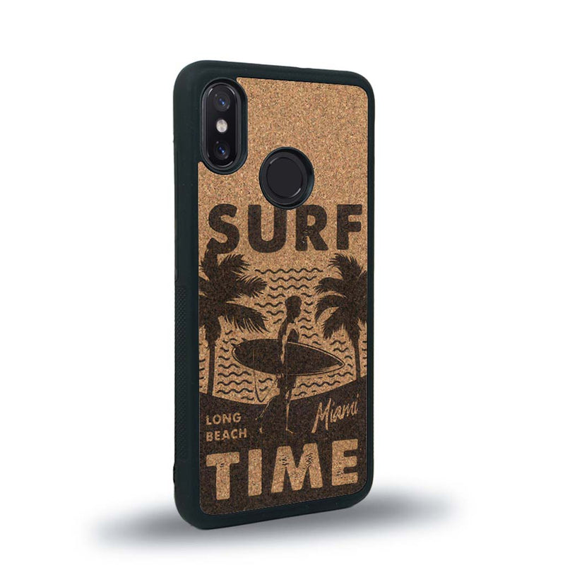 Coque de protection en bois véritable fabriquée en France pour Xiaomi Mi 8 sur le thème chill avec un motif représentant une silouhette tenant une planche de surf sur une plage entouré de palmiers et les mots "Surf Time Long Beach Miami"