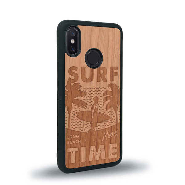 Coque de protection en bois véritable fabriquée en France pour Xiaomi Mi 8 sur le thème chill avec un motif représentant une silouhette tenant une planche de surf sur une plage entouré de palmiers et les mots "Surf Time Long Beach Miami"