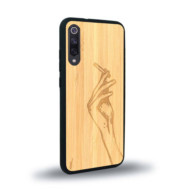 Coque de protection en bois véritable fabriquée en France pour Xiaomi Mi 9SE représentant une main de femme tenant une cigarette de type line art en collaboration avec l'artiste Maud Dabs