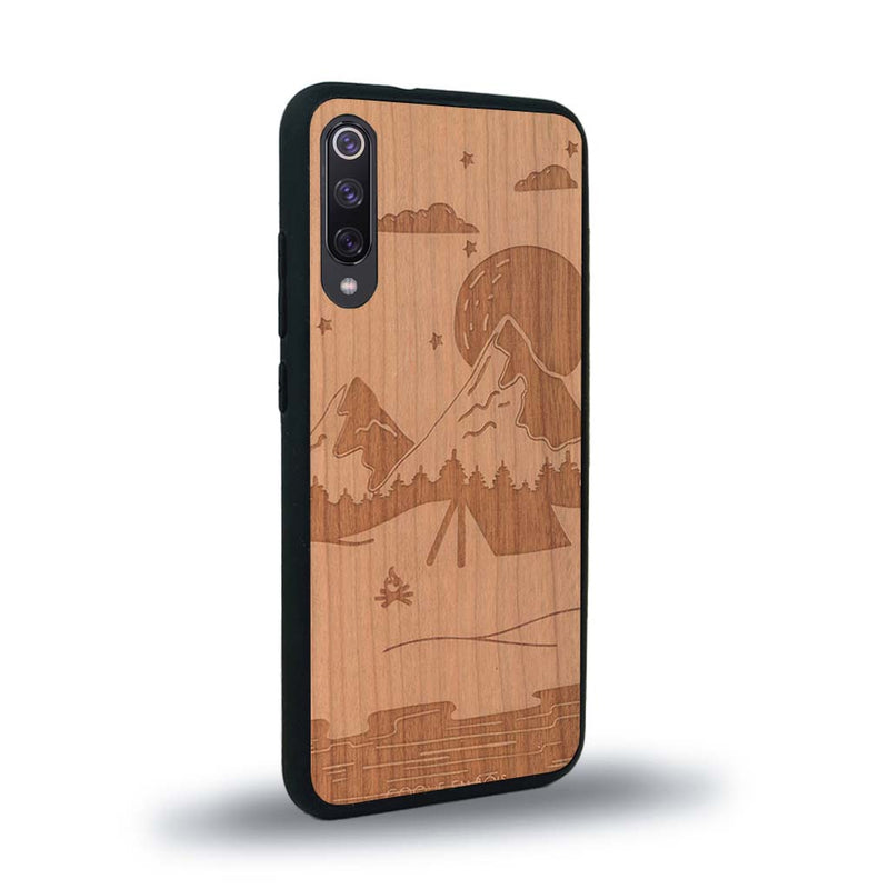 Coque de protection en bois véritable fabriquée en France pour Xiaomi Mi 9SE sur le thème du camping en pleine nature représentant une tente avec un feu de camp entouré de montagnes