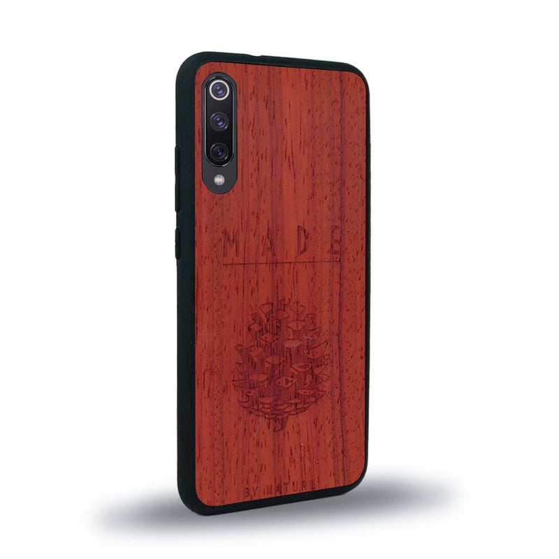 Coque de protection en bois véritable fabriquée en France pour Xiaomi Mi 9SE sur le thème de la nature et des arbres avec une gravure représentant une pomme de pin et la phrase "made by nature"