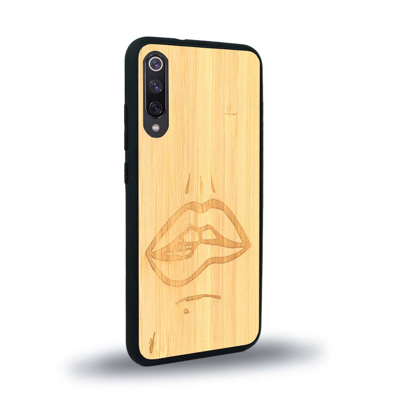 Coque de protection en bois véritable fabriquée en France pour Xiaomi Mi 9SE représentant de manière minimaliste une bouche de féminine se mordant le coin de la lèvre de manière sensuelle dessinée à la main par l'artiste Maud Dabs