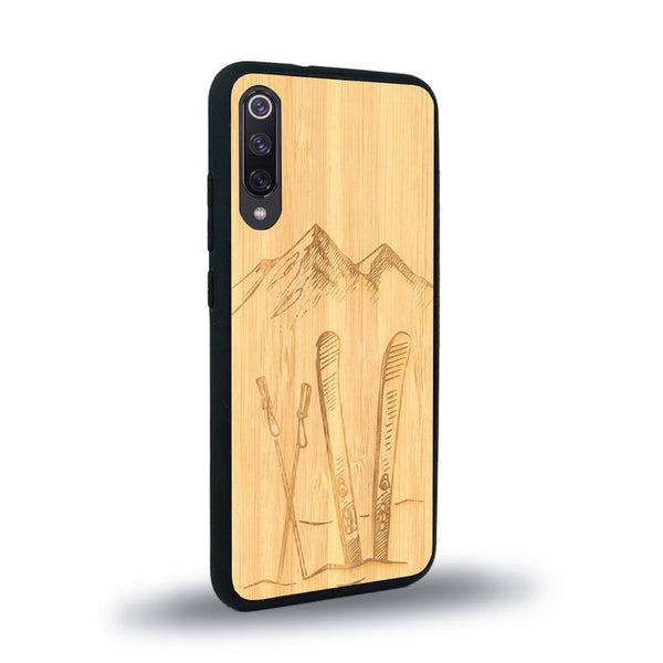 Coque de protection en bois véritable fabriquée en France pour Xiaomi Mi 9SE sur le thème de la montagne, du ski et de la neige avec un motif représentant une paire de ski plantée dans la neige avec en fond des montagnes enneigées