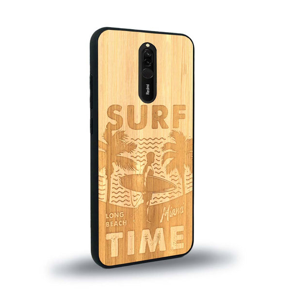 Coque de protection en bois véritable fabriquée en France pour Xiaomi Mi 9T sur le thème chill avec un motif représentant une silouhette tenant une planche de surf sur une plage entouré de palmiers et les mots "Surf Time Long Beach Miami"