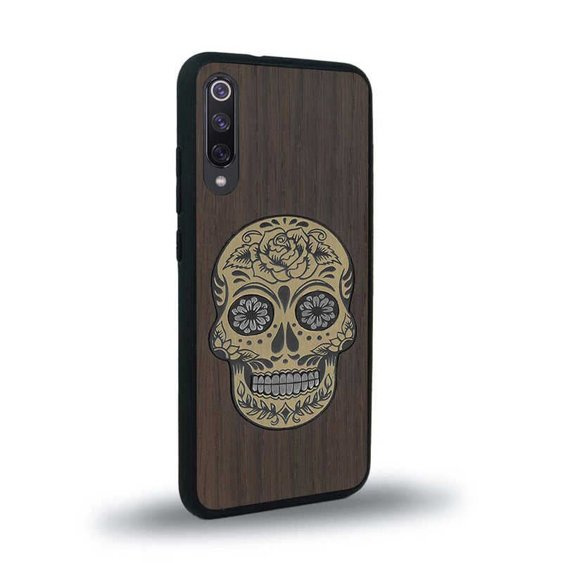 Coque de protection en bois véritable fabriquée en France pour Xiaomi Mi A3 alliant du chêne fumé avec du métal argenté et doré représentant une tête de mort mexicaine sur le thème Dia de los Muertos