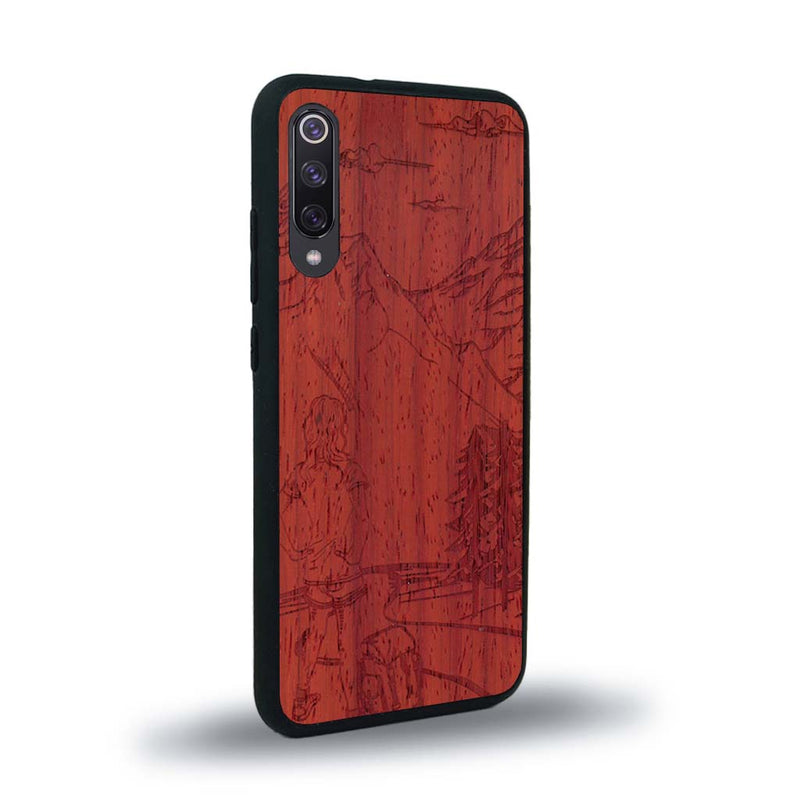 Coque de protection en bois véritable fabriquée en France pour Xiaomi Mi A3 sur le thème de la randonnée en montagne et de l'aventure avec une gravure représentant une femme de dos face à un paysage de nature
