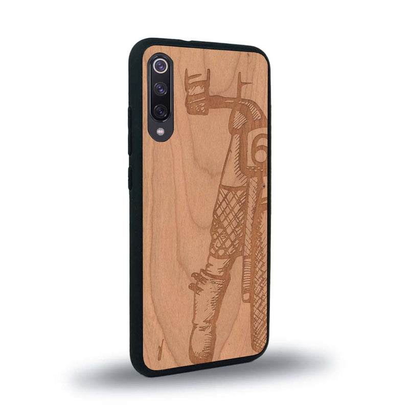 Coque de protection en bois véritable fabriquée en France pour Xiaomi Mi A3 représentant une vue de face d'une femme sur une moto vintage dessinée à la main par l'artiste Maud Dabs