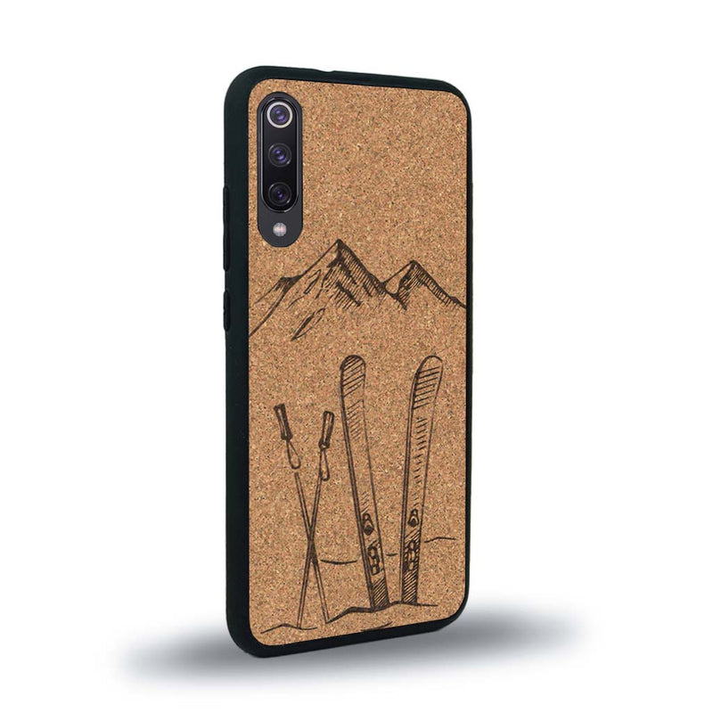 Coque de protection en bois véritable fabriquée en France pour Xiaomi Mi A3 sur le thème de la montagne, du ski et de la neige avec un motif représentant une paire de ski plantée dans la neige avec en fond des montagnes enneigées