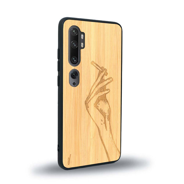 Coque de protection en bois véritable fabriquée en France pour Xiaomi Mi Note 10 Pro représentant une main de femme tenant une cigarette de type line art en collaboration avec l'artiste Maud Dabs