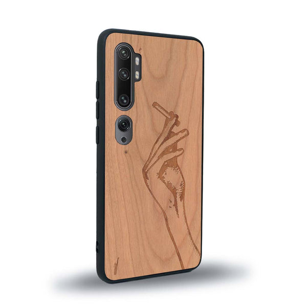 Coque de protection en bois véritable fabriquée en France pour Xiaomi Mi Note 10 Pro représentant une main de femme tenant une cigarette de type line art en collaboration avec l'artiste Maud Dabs