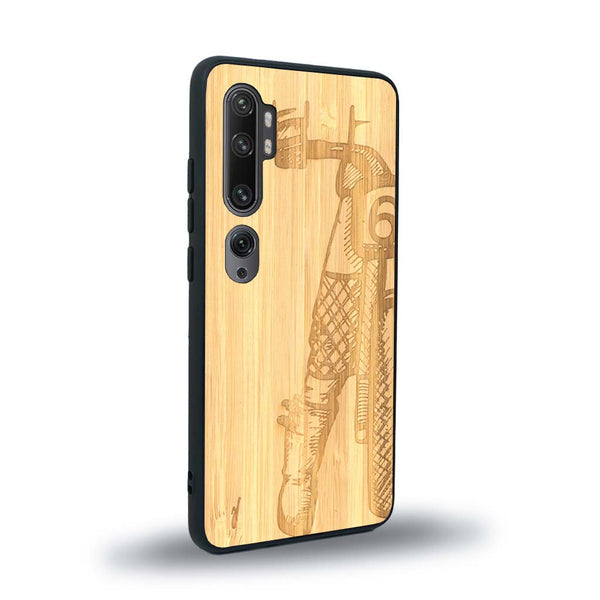 Coque de protection en bois véritable fabriquée en France pour Xiaomi Mi Note 10 Pro représentant une vue de face d'une femme sur une moto vintage dessinée à la main par l'artiste Maud Dabs