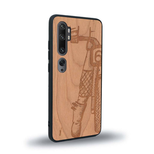 Coque de protection en bois véritable fabriquée en France pour Xiaomi Mi Note 10 Pro représentant une vue de face d'une femme sur une moto vintage dessinée à la main par l'artiste Maud Dabs
