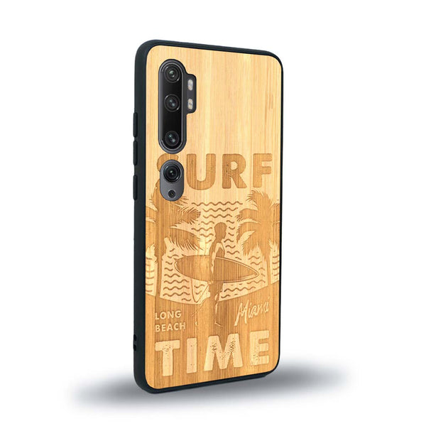 Coque de protection en bois véritable fabriquée en France pour Xiaomi Mi Note 10 Pro sur le thème chill avec un motif représentant une silouhette tenant une planche de surf sur une plage entouré de palmiers et les mots "Surf Time Long Beach Miami"