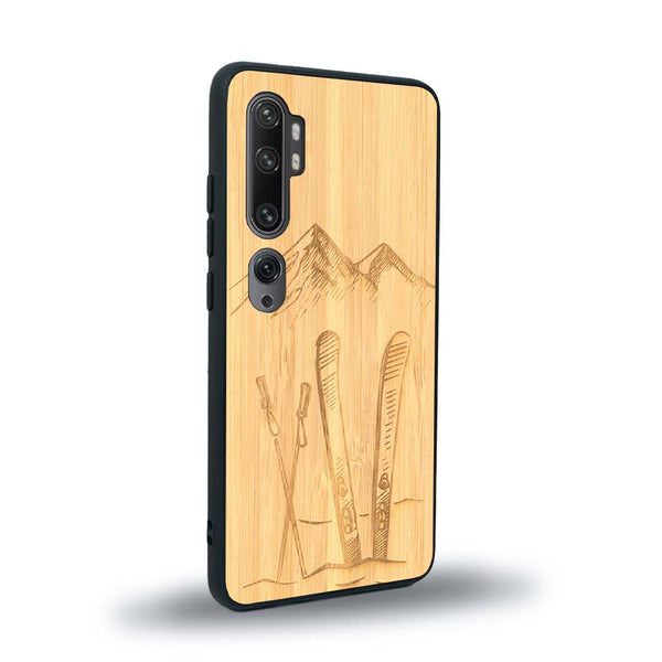 Coque de protection en bois véritable fabriquée en France pour Xiaomi Mi Note 10 Pro sur le thème de la montagne, du ski et de la neige avec un motif représentant une paire de ski plantée dans la neige avec en fond des montagnes enneigées