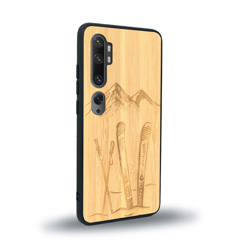 Coque de protection en bois véritable fabriquée en France pour Xiaomi Mi Note 10 Pro sur le thème de la montagne, du ski et de la neige avec un motif représentant une paire de ski plantée dans la neige avec en fond des montagnes enneigées
