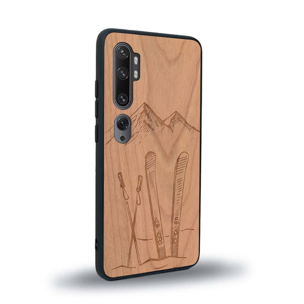 Coque de protection en bois véritable fabriquée en France pour Xiaomi Mi Note 10 Pro sur le thème de la montagne, du ski et de la neige avec un motif représentant une paire de ski plantée dans la neige avec en fond des montagnes enneigées