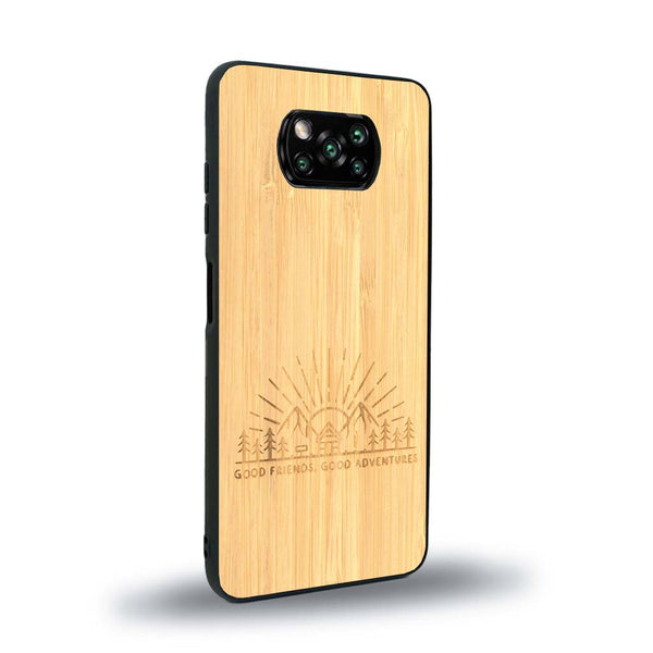 Coque de protection en bois véritable fabriquée en France pour Xiaomi Poco X3 Nfc sur le thème chill et nature avec un motif représentant un levé de soleil sur un paysage de montagne avec des sapins et un chalet et la phrase "Good friends, good adventure"