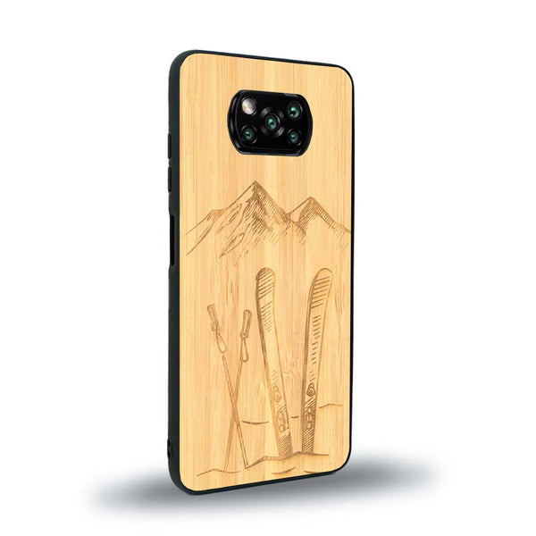 Coque de protection en bois véritable fabriquée en France pour Xiaomi Poco X3 Nfc sur le thème de la montagne, du ski et de la neige avec un motif représentant une paire de ski plantée dans la neige avec en fond des montagnes enneigées