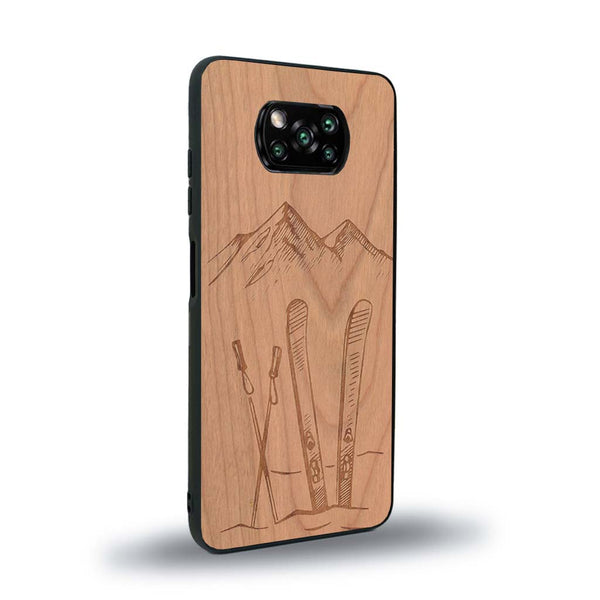 Coque de protection en bois véritable fabriquée en France pour Xiaomi Poco X3 Nfc sur le thème de la montagne, du ski et de la neige avec un motif représentant une paire de ski plantée dans la neige avec en fond des montagnes enneigées