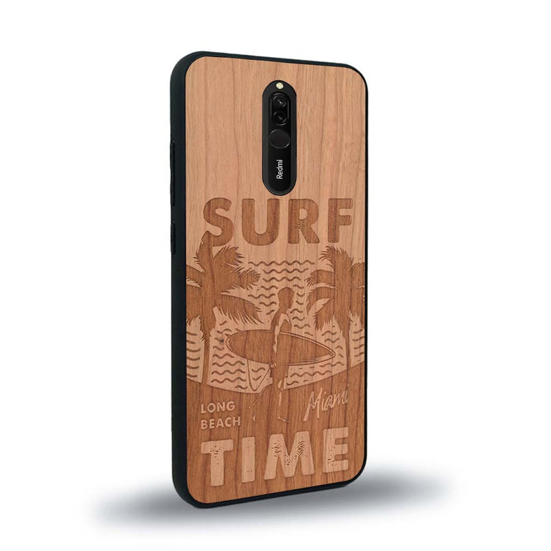 Coque de protection en bois véritable fabriquée en France pour Xiaomi Redmi 8 sur le thème chill avec un motif représentant une silouhette tenant une planche de surf sur une plage entouré de palmiers et les mots "Surf Time Long Beach Miami"