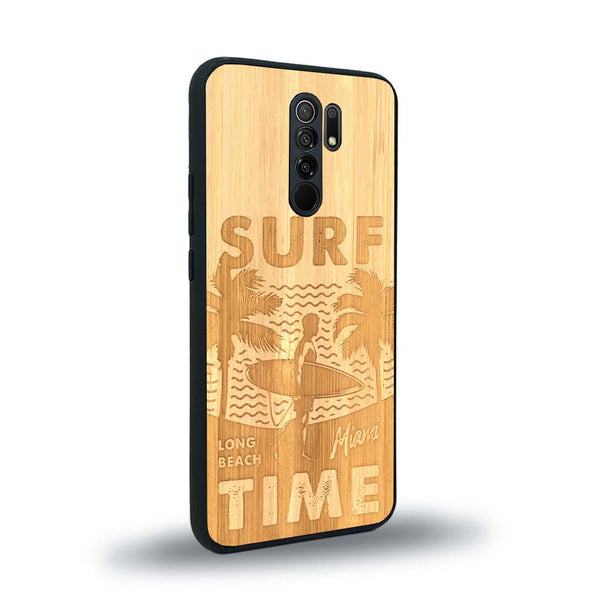 Coque de protection en bois véritable fabriquée en France pour Xiaomi Redmi 9 sur le thème chill avec un motif représentant une silouhette tenant une planche de surf sur une plage entouré de palmiers et les mots "Surf Time Long Beach Miami"