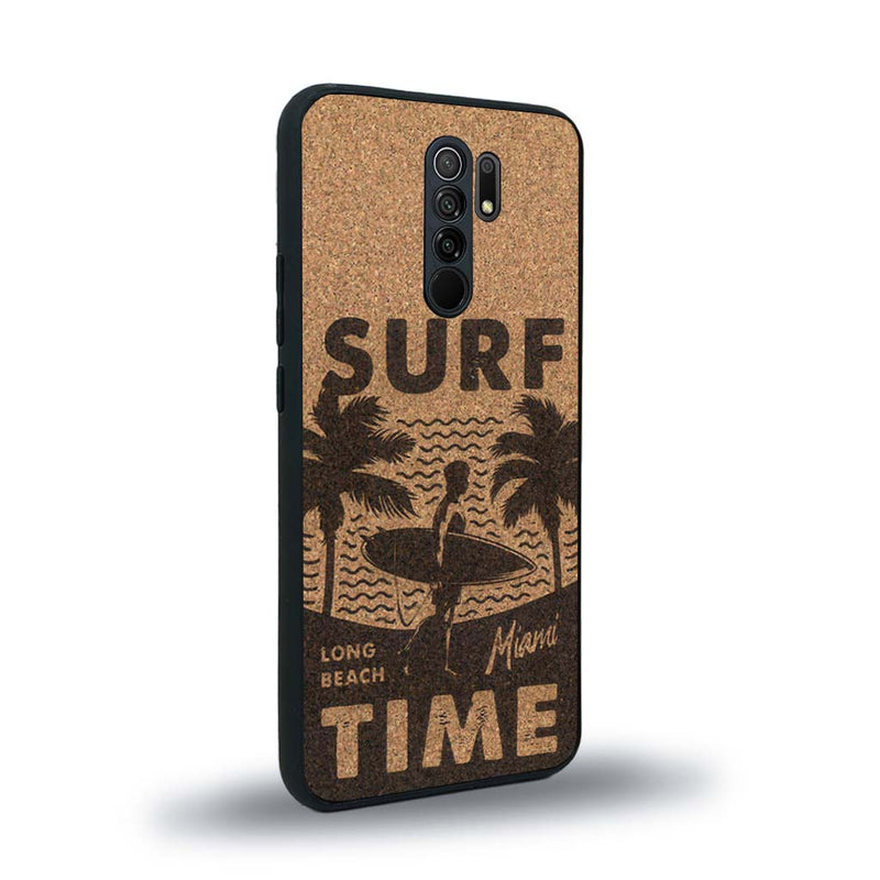 Coque de protection en bois véritable fabriquée en France pour Xiaomi Redmi 9 sur le thème chill avec un motif représentant une silouhette tenant une planche de surf sur une plage entouré de palmiers et les mots "Surf Time Long Beach Miami"