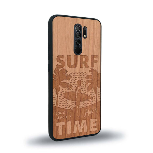 Coque de protection en bois véritable fabriquée en France pour Xiaomi Redmi 9 sur le thème chill avec un motif représentant une silouhette tenant une planche de surf sur une plage entouré de palmiers et les mots "Surf Time Long Beach Miami"