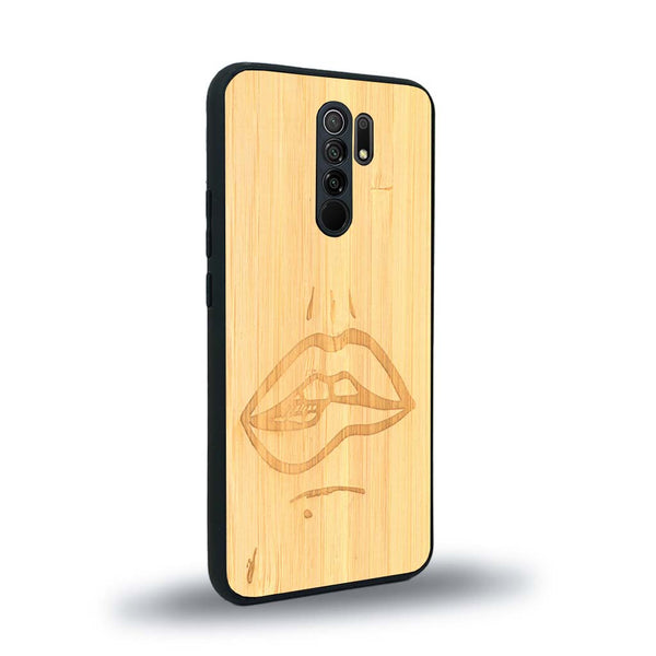 Coque de protection en bois véritable fabriquée en France pour Xiaomi Redmi 9 représentant de manière minimaliste une bouche de féminine se mordant le coin de la lèvre de manière sensuelle dessinée à la main par l'artiste Maud Dabs
