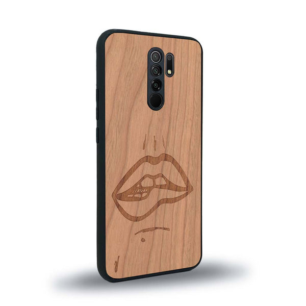 Coque de protection en bois véritable fabriquée en France pour Xiaomi Redmi 9 représentant de manière minimaliste une bouche de féminine se mordant le coin de la lèvre de manière sensuelle dessinée à la main par l'artiste Maud Dabs