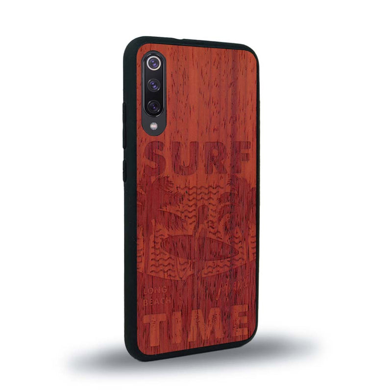 Coque de protection en bois véritable fabriquée en France pour Xiaomi Redmi 9A sur le thème chill avec un motif représentant une silouhette tenant une planche de surf sur une plage entouré de palmiers et les mots "Surf Time Long Beach Miami"