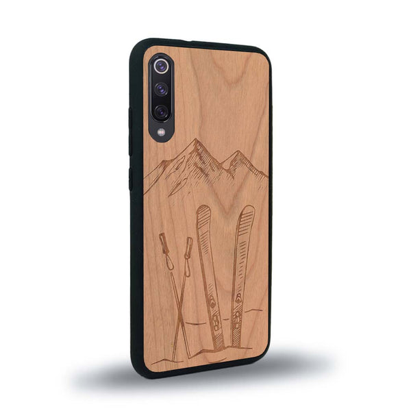 Coque de protection en bois véritable fabriquée en France pour Xiaomi Redmi 9A sur le thème de la montagne, du ski et de la neige avec un motif représentant une paire de ski plantée dans la neige avec en fond des montagnes enneigées