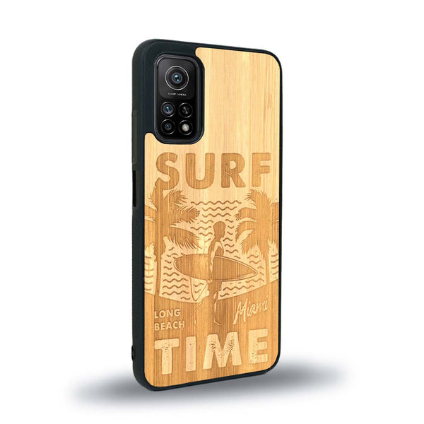 Coque de protection en bois véritable fabriquée en France pour Xiaomi Redmi Note 10 sur le thème chill avec un motif représentant une silouhette tenant une planche de surf sur une plage entouré de palmiers et les mots "Surf Time Long Beach Miami"